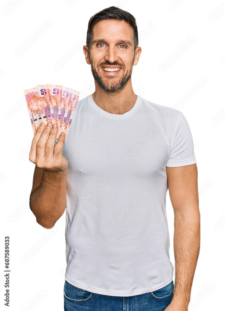 Handsome man with beard holding south african 50 rand banknotes looking positive and happy standing and smiling with a confident smile showing teeth Handsome man with beard holding south african 50 rand banknotes looking positive and happy standing and smiling with a confident smile showing teeth