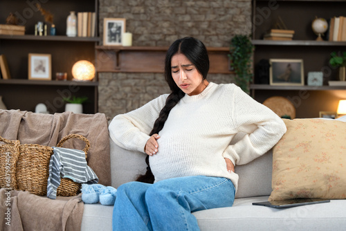 Pregnant woman experiencing contractions while sitting at home on the couch photo