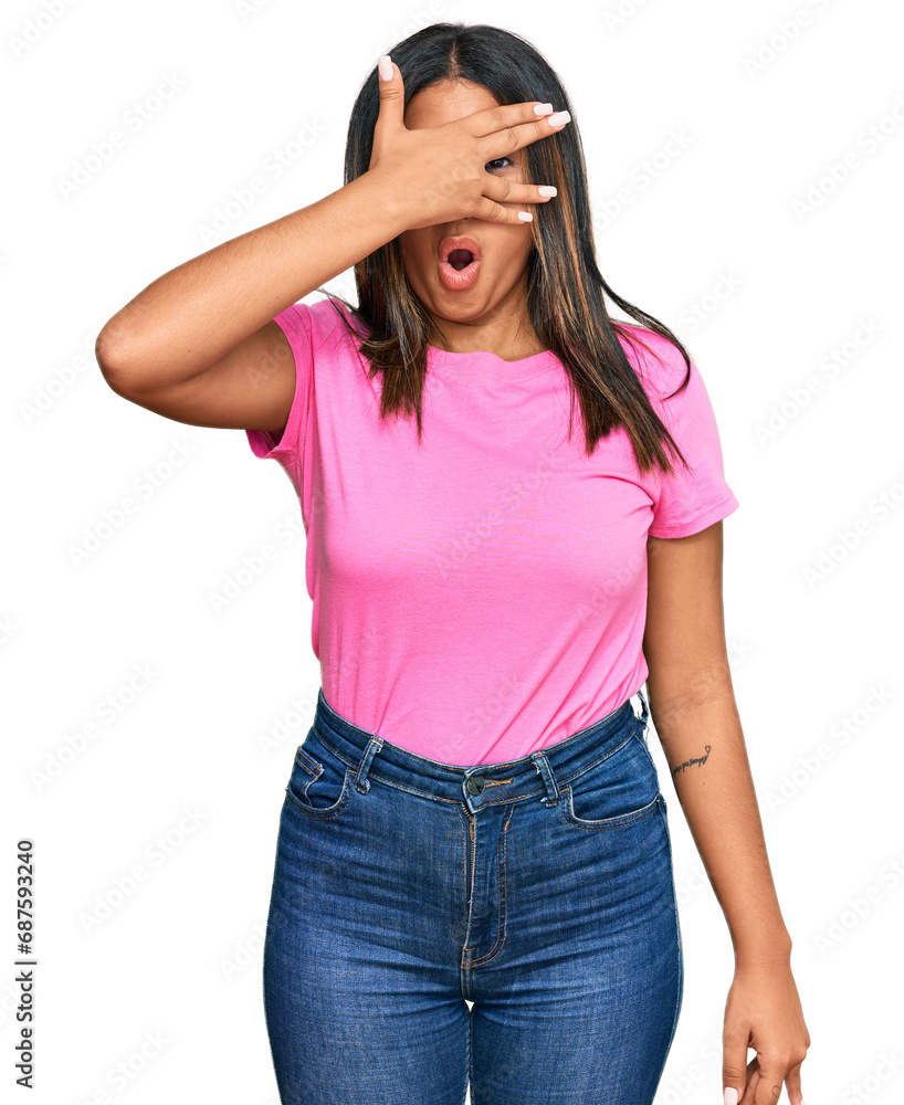 Young latin girl wearing casual clothes peeking in shock covering face and eyes with hand, looking through fingers with embarrassed expression. Young latin girl wearing casual clothes peeking in shock covering face and eyes with hand, looking through fingers with embarrassed expression.