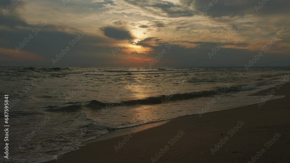 Seascape at sunset. Ocean waves crash against sandy beach. Seascape at sunset. Ocean waves crash against sandy beach.