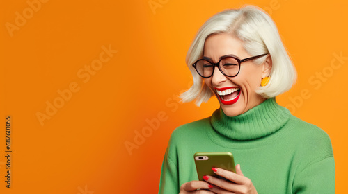 Wallpaper Mural An elderly woman smiling and laughing with her phone against orange background. Torontodigital.ca