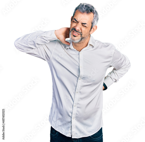 Middle age hispanic with grey hair wearing casual white shirt suffering of neck ache injury, touching neck with hand, muscular pain © Krakenimages.com