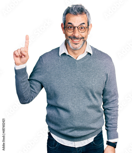 Tableau sur toile Middle age hispanic with grey hair wearing glasses showing and pointing up with finger number one while smiling confident and happy