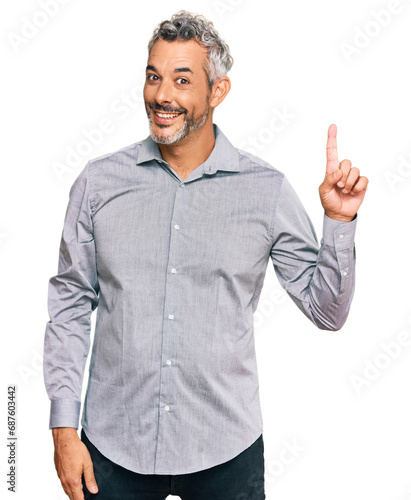 Middle age grey-haired man wearing casual clothes showing and pointing up with finger number one while smiling confident and happy.