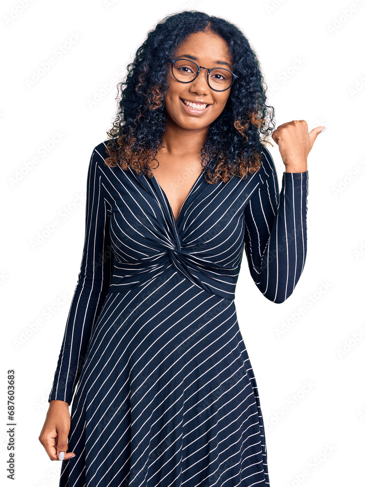 Young african american woman wearing casual clothes and glasses smiling with happy face looking and pointing to the side with thumb up. Young african american woman wearing casual clothes and glasses smiling with happy face looking and pointing to the side with thumb up.