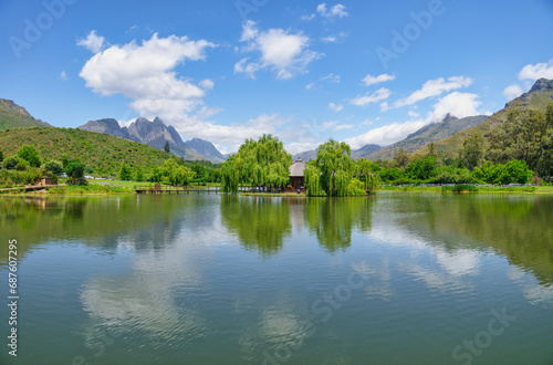 Postcard Cafe in the middle of the lake at Stark-Conde Wines and the Jonkershoek Mountains range in the background with Stellenbosch Mountain peak touching the clouds, Cape Town, South Africa