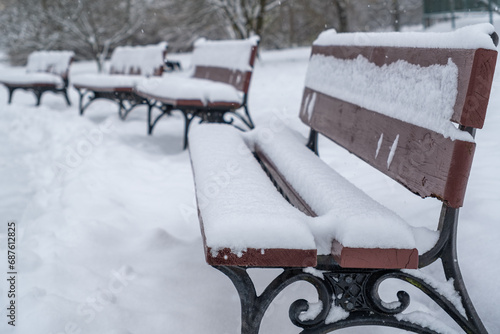 Winter park benches are covered with fresh snow
