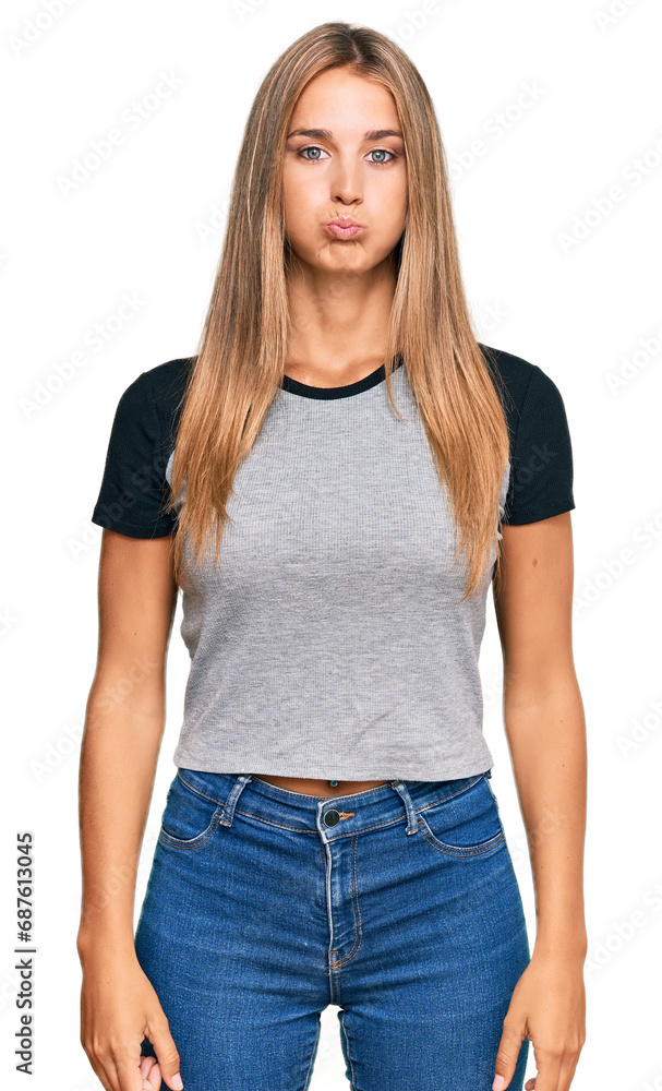 Obraz premium Young blonde woman wearing casual clothes puffing cheeks with funny face. mouth inflated with air, crazy expression.