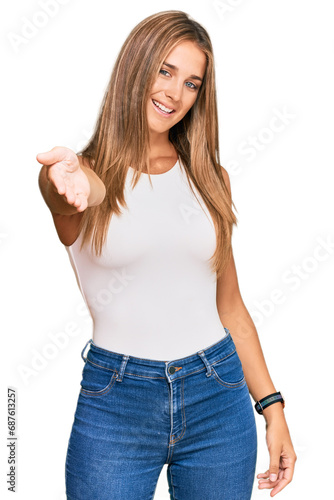 Young blonde woman wearing casual style with sleeveless shirt smiling cheerful offering palm hand giving assistance and acceptance. © Krakenimages.com
