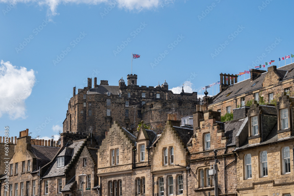 Row of old stone buildings with a castle backdrop along the royal mile in Scotland