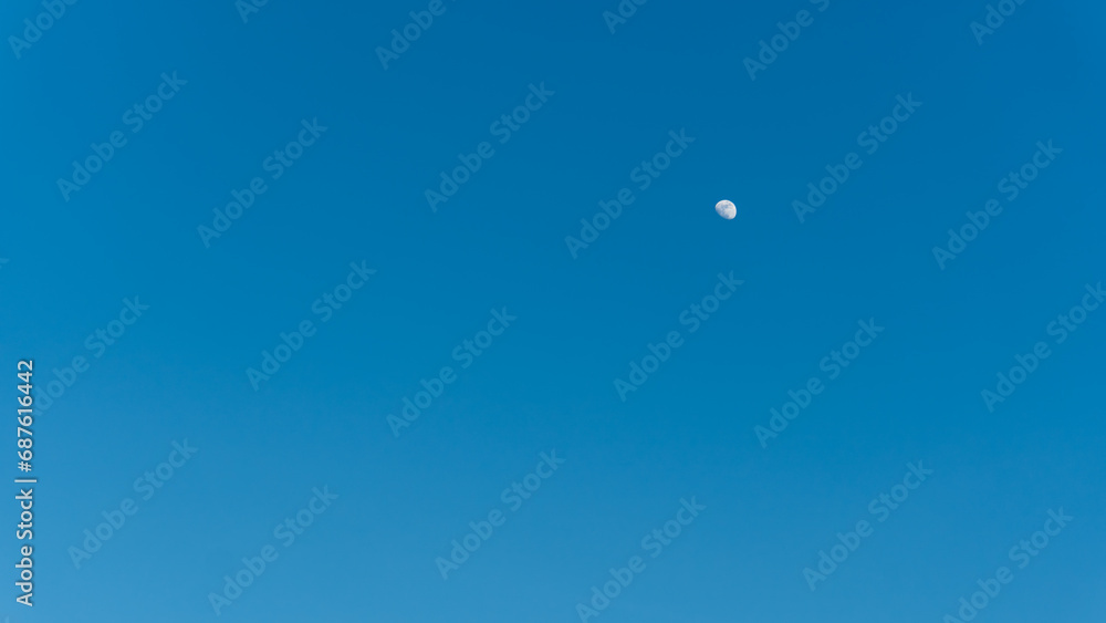 Half bright moon on blue sky background. Half bright moon on blue sky background.