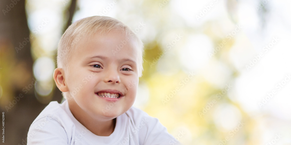 Portrait of a laughing boy with Down syndrome. child outdoors. A handsome boy rejoices.
Portrait of a laughing boy with Down syndrome. child outdoors. A handsome boy rejoices.