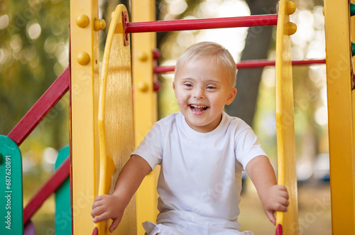 Portrait of a laughing boy with Down syndrome. child outdoors. A handsome boy rejoices. 