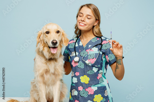 Young veterinarian woman she wear uniform stethoscope heal exam hug embrace retriever dog do vaccine injection isolated on plain pastel light blue background studio portrait. Pet health care concept.