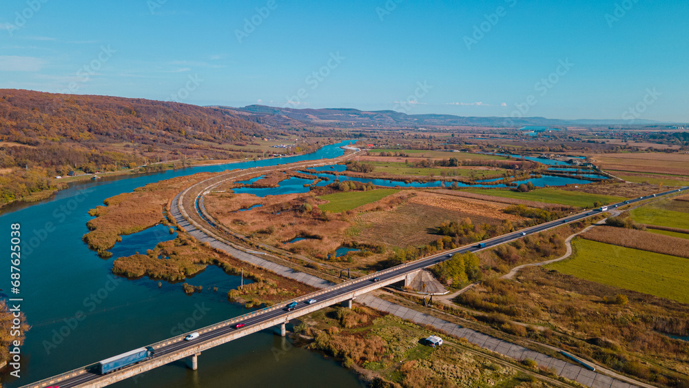 Road bridge over Olt river, autumn colours in Romania | drone view