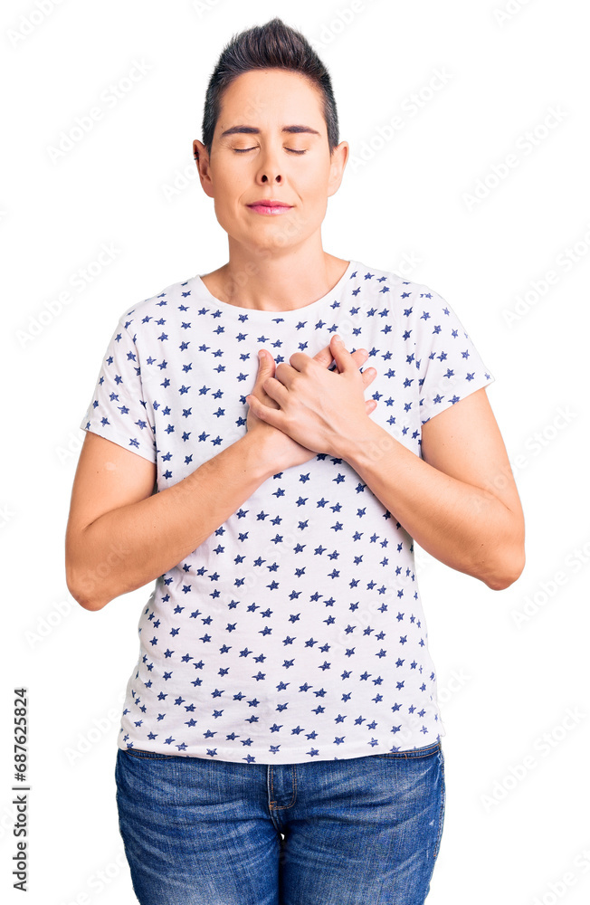 Young woman with short hair wearing casual clothes smiling with hands on chest with closed eyes and grateful gesture on face. health concept. Young woman with short hair wearing casual clothes smiling with hands on chest with closed eyes and grateful gesture on face. health concept.