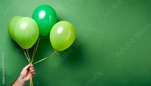 stylish birthday party or holidays with balloons three green balloons on the green background with copy space for text hand holding three bright colorful balloons indoor greeting background