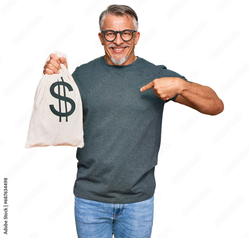 Middle age grey-haired man holding dollars bag pointing finger to one self smiling happy and proud Middle age grey-haired man holding dollars bag pointing finger to one self smiling happy and proud