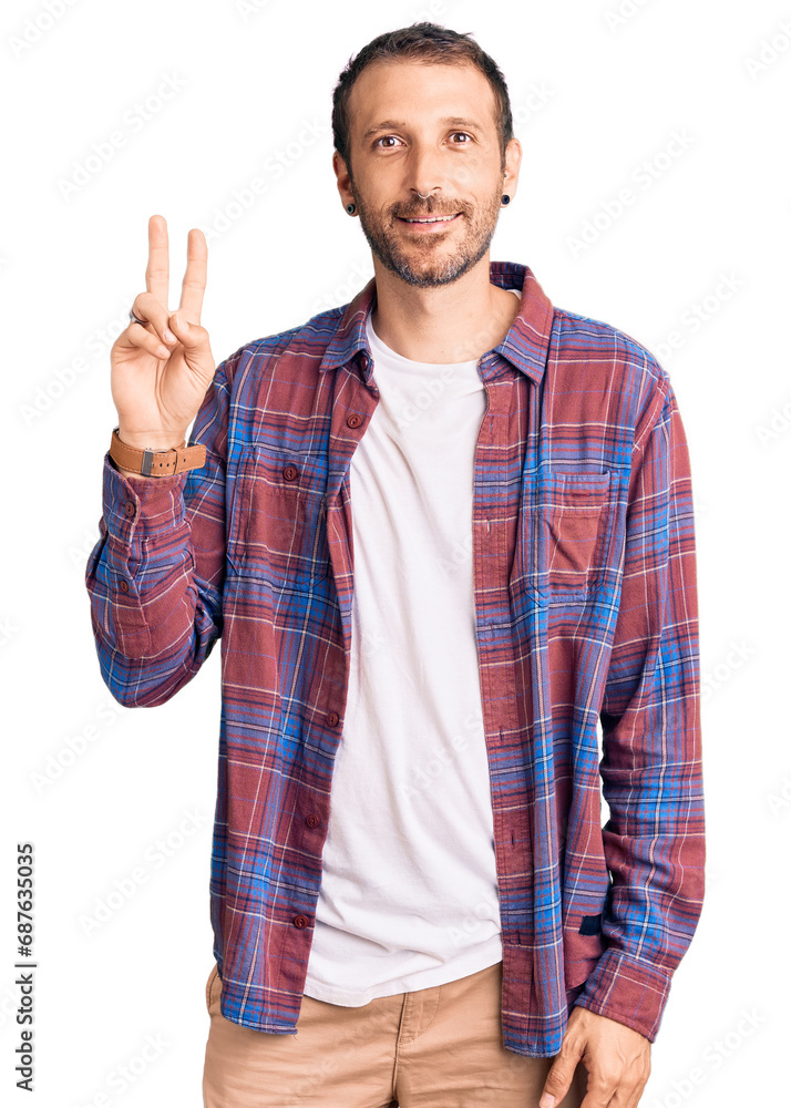 Young handsome man wearing casual clothes smiling looking to the camera showing fingers doing victory sign. number two. Young handsome man wearing casual clothes smiling looking to the camera showing fingers doing victory sign. number two.