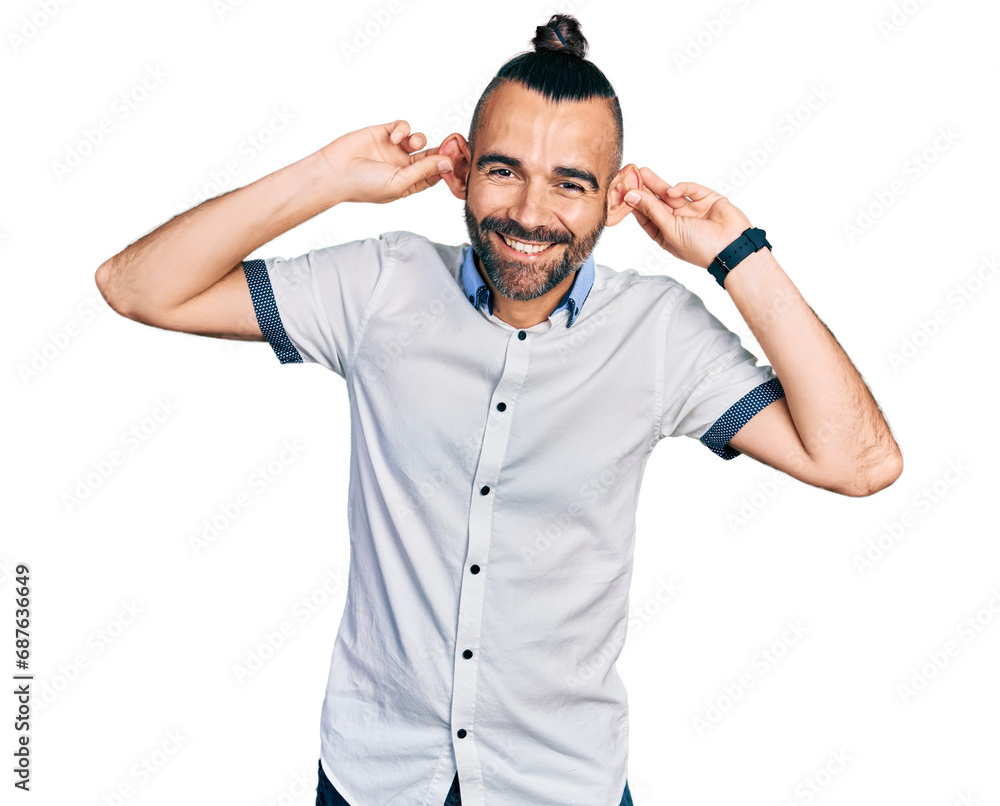Hispanic man with ponytail wearing casual white shirt smiling pulling ears with fingers, funny gesture. audition problem Hispanic man with ponytail wearing casual white shirt smiling pulling ears with fingers, funny gesture. audition problem