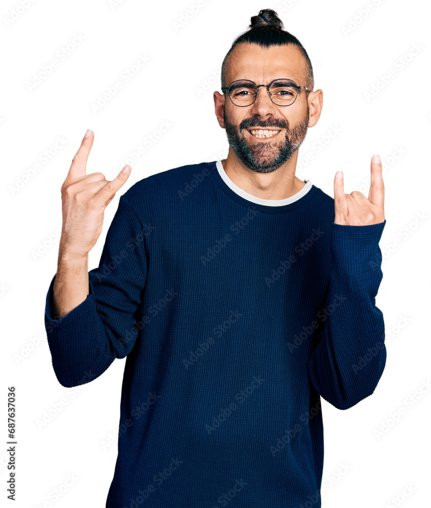 Hispanic man with ponytail wearing casual sweater and glasses shouting with crazy expression doing rock symbol with hands up. music star. heavy concept. Hispanic man with ponytail wearing casual sweater and glasses shouting with crazy expression doing rock symbol with hands up. music star. heavy concept.