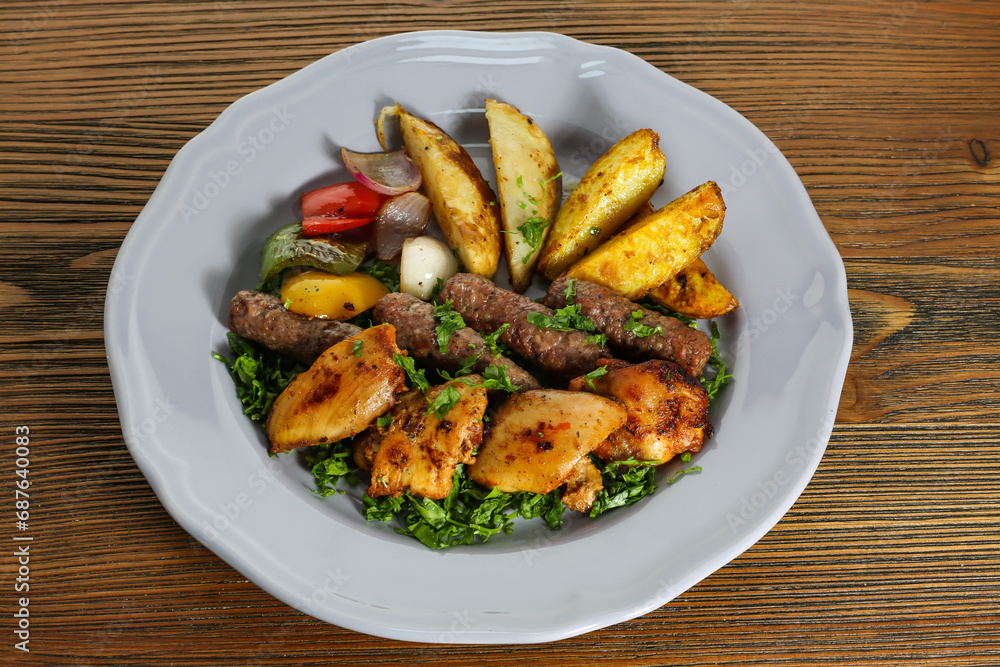 Mix kofta and shish tawook kabab with potato veggies, tomato, onion and coriander served in dish isolated on table side view of arabic food Mix kofta and shish tawook kabab with potato veggies, tomato, onion and coriander served in dish isolated on table side view of arabic food