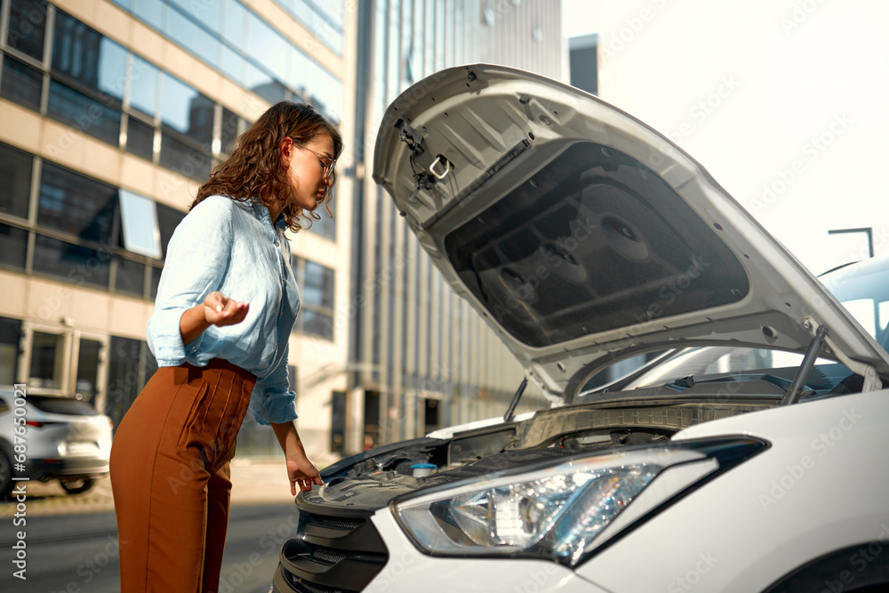 Woman standing near broken car with open hood Woman standing near broken car with open hood