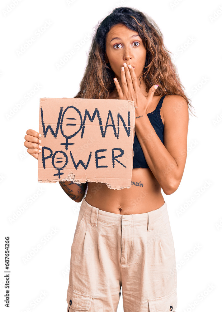 Young hispanic woman with tattoo holding woman power banner covering mouth with hand, shocked and afraid for mistake. surprised expression Young hispanic woman with tattoo holding woman power banner covering mouth with hand, shocked and afraid for mistake. surprised expression