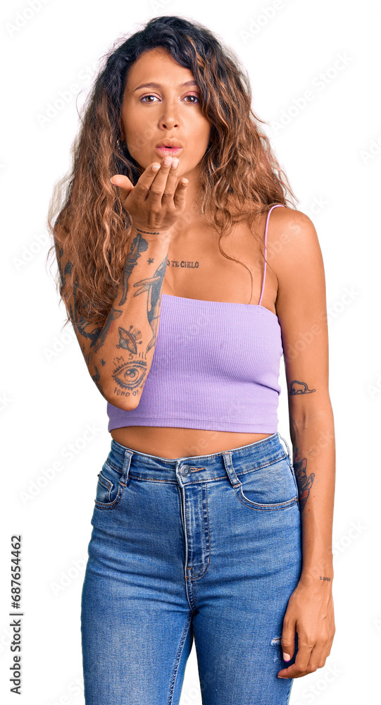 Young hispanic woman with tattoo wearing casual clothes looking at the camera blowing a kiss with hand on air being lovely and sexy. love expression. Young hispanic woman with tattoo wearing casual clothes looking at the camera blowing a kiss with hand on air being lovely and sexy. love expression.