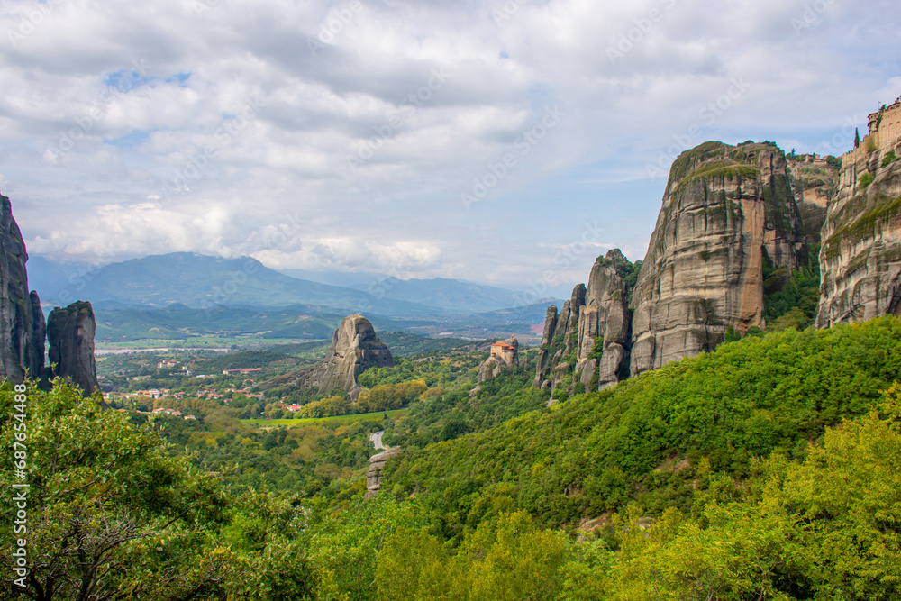 Meteora rock towers Greece. Stunning  landscape View at mountains and green forest against epic blue sky with clouds. UNESCO heritage list object.