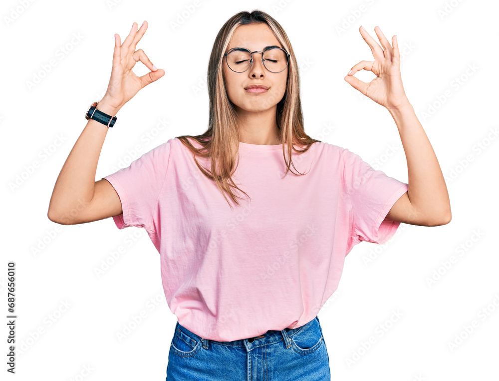 Hispanic young woman wearing casual t shirt and glasses relax and smiling with eyes closed doing meditation gesture with fingers. yoga concept. Hispanic young woman wearing casual t shirt and glasses relax and smiling with eyes closed doing meditation gesture with fingers. yoga concept.