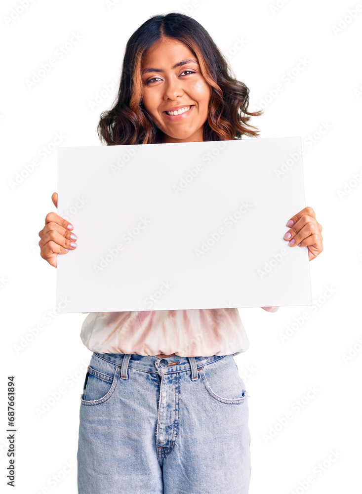 Young beautiful mixed race woman holding cardboard banner with blank space looking positive and happy standing and smiling with a confident smile showing teeth Young beautiful mixed race woman holding cardboard banner with blank space looking positive and happy standing and smiling with a confident smile showing teeth