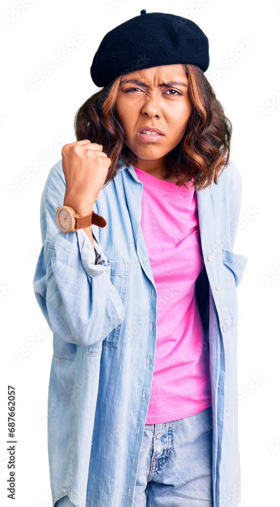 Young beautiful mixed race woman wearing french look with beret angry and mad raising fist frustrated and furious while shouting with anger. rage and aggressive concept. Young beautiful mixed race woman wearing french look with beret angry and mad raising fist frustrated and furious while shouting with anger. rage and aggressive concept.