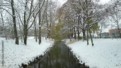 Fly over winter city stream calm river covered in snow, drone