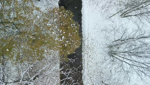 Fly over winter city stream calm river covered in snow, drone