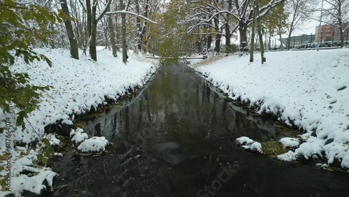 Fly over winter city stream calm river covered in snow, drone