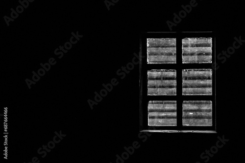 View through the window from inside the room. Window inside a dark room. Through the window of the room you can see the wall of the log house outside. Through the window you can see the log house 