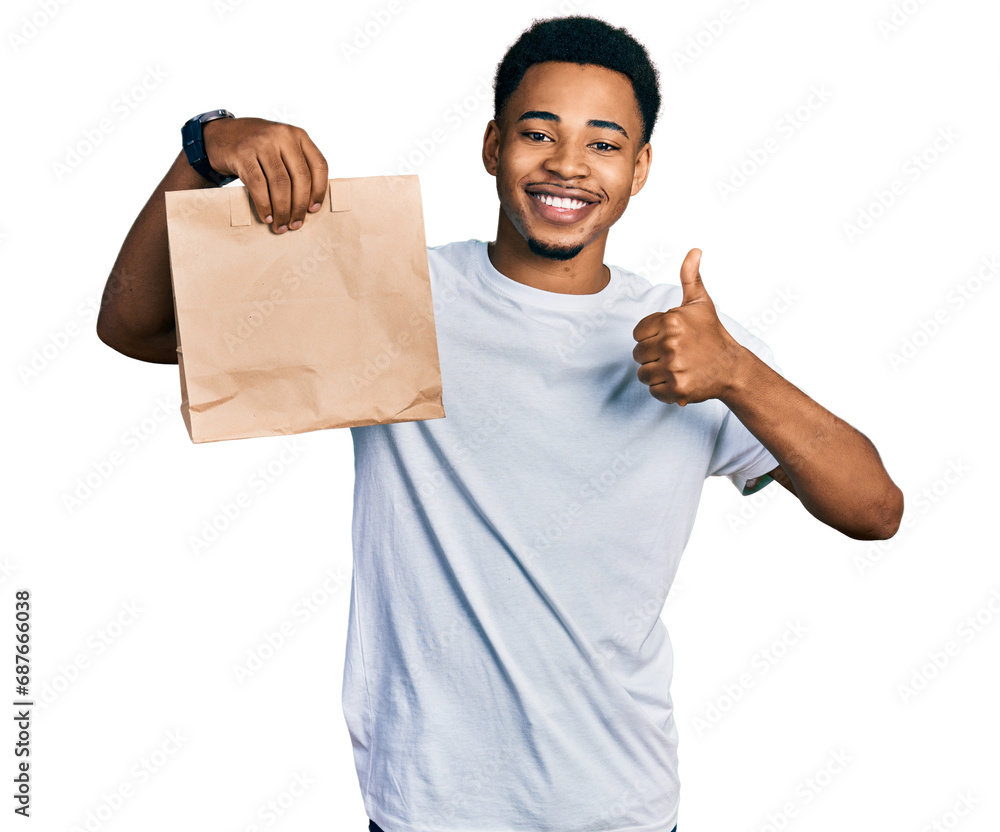 Young african american man holding take away paper bag smiling happy and positive, thumb up doing excellent and approval sign Young african american man holding take away paper bag smiling happy and positive, thumb up doing excellent and approval sign