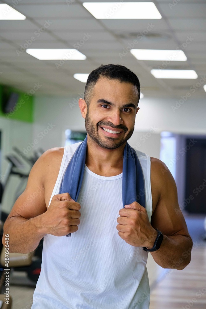 Portrait of a strong Hispanic man at a gym smiling and looking at camera.