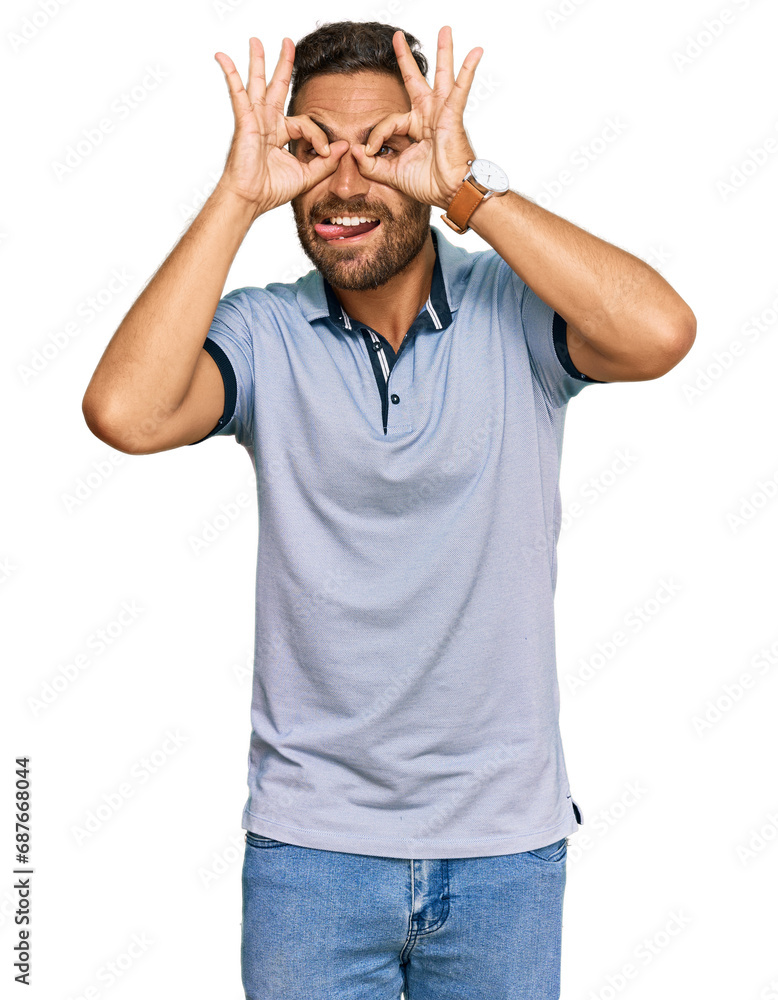 Handsome man with beard wearing casual clothes doing ok gesture like binoculars sticking tongue out, eyes looking through fingers. crazy expression. Handsome man with beard wearing casual clothes doing ok gesture like binoculars sticking tongue out, eyes looking through fingers. crazy expression.