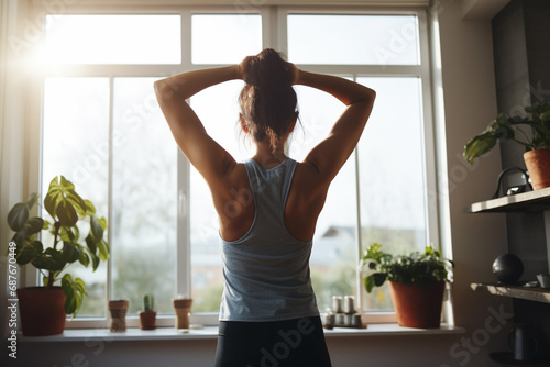 Rear view of young woman in sportswear doing yoga at home
