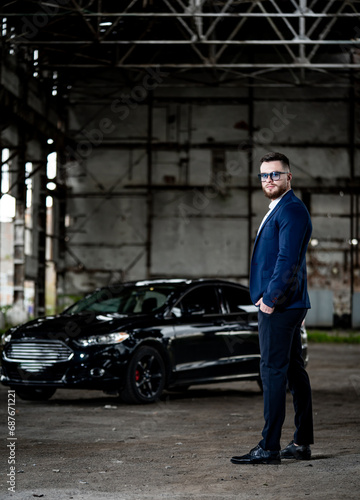 A Man in a Suit Standing Next to a Black Car. A man in a suit standing next to a black car