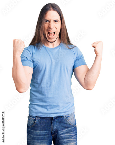 Young adult man with long hair wearing casual clothes screaming proud, celebrating victory and success very excited with raised arms