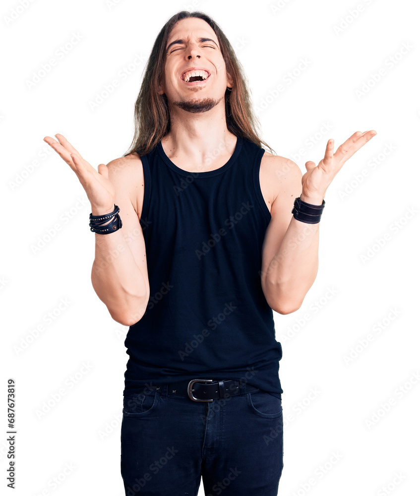 Young adult man with long hair wearing rocker style with black clothes and contact lenses celebrating mad and crazy for success with arms raised and closed eyes screaming excited. winner concept Young adult man with long hair wearing rocker style with black clothes and contact lenses celebrating mad and crazy for success with arms raised and closed eyes screaming excited. winner concept