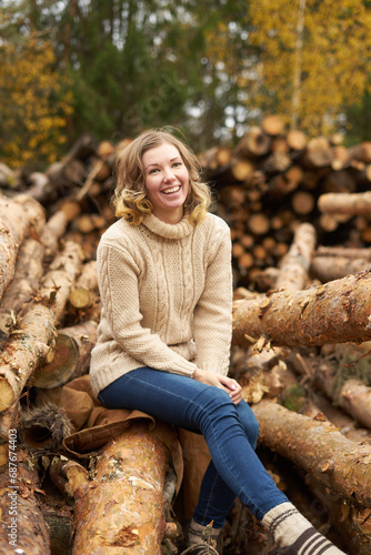 smiling woman in front of wooden logs.