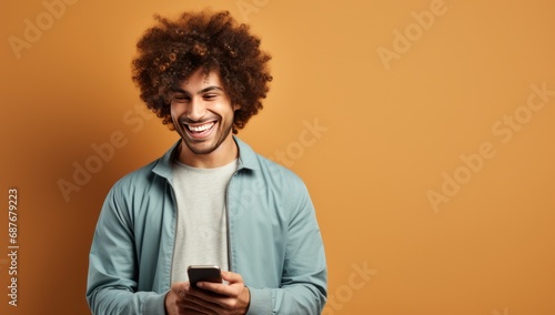 a man smiling at a cell phone while leaning against the wall,