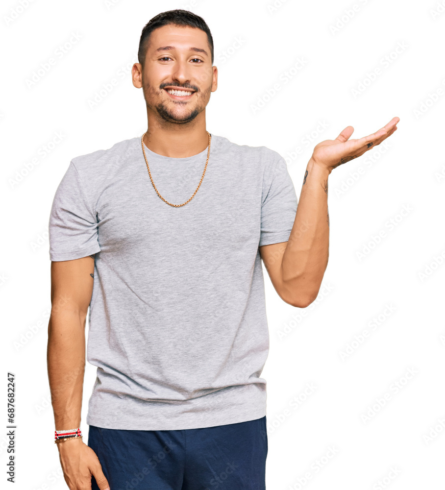 Handsome man with tattoos wearing 90s style smiling cheerful presenting and pointing with palm of hand looking at the camera.