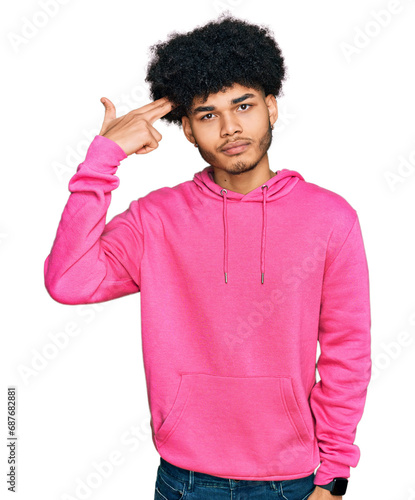 Young african american man with afro hair wearing casual pink sweatshirt shooting and killing oneself pointing hand and fingers to head like gun, suicide gesture.