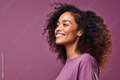 A woman with curly hair is smiling and wearing a purple shirt photo
