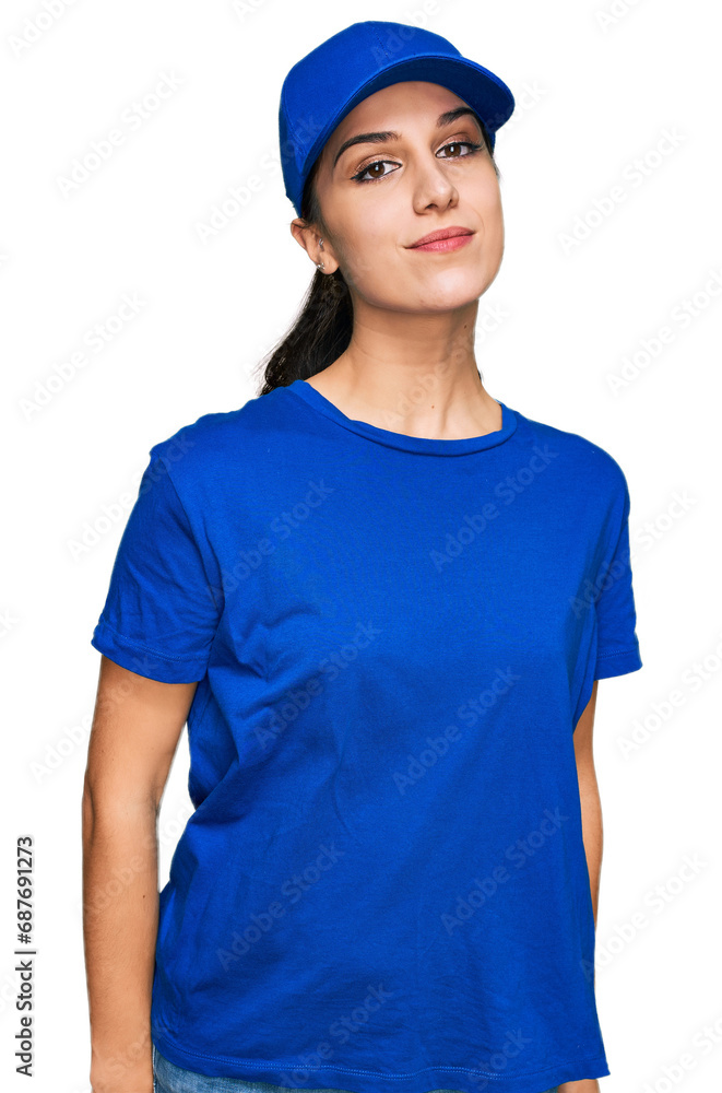 Young hispanic girl wearing delivery courier uniform relaxed with serious expression on face. simple and natural looking at the camera. Young hispanic girl wearing delivery courier uniform relaxed with serious expression on face. simple and natural looking at the camera.